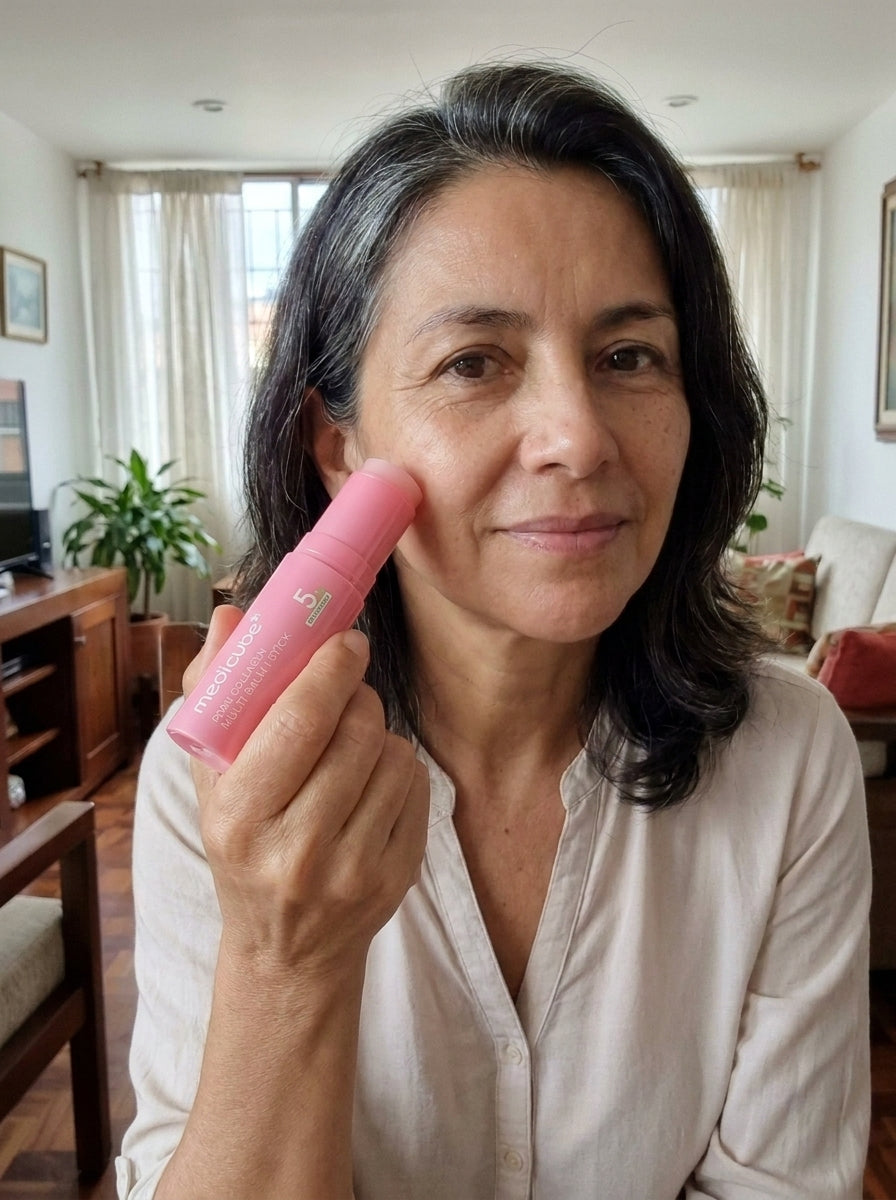 Mujer de 50 años aplicando el bálsamo Medicube cerca del pómulo