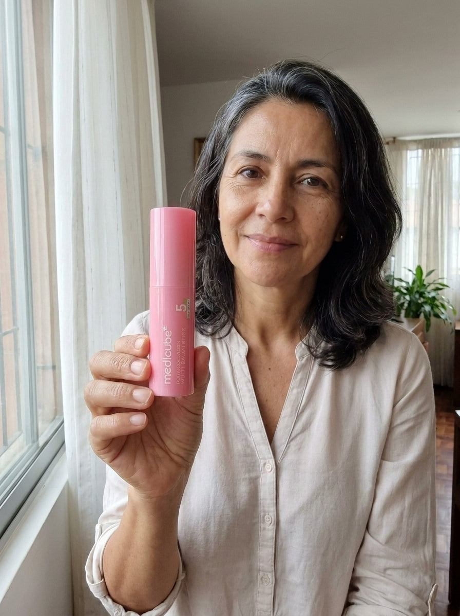 Mujer de 50 años con el bálsamo Medicube y un café junto a la ventana